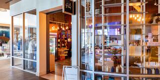 A stylish retail space with a modern vibe, featuring bright lighting, clothing displays, and various products showcased behind glass.