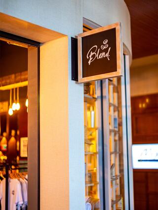 A stylish entrance to a shop named "Blend," featuring elegant lighting, a wooden sign, and a glimpse of merchandise through glass doors.