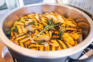 A platter of grilled salmon fillets, beautifully marked with grill lines and garnished with fresh herbs.