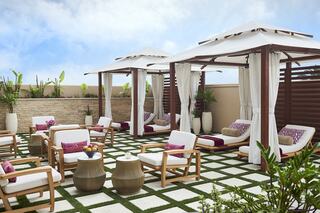 Luxurious outdoor lounge area features cabanas, plush seating, and greenery, creating a serene atmosphere for relaxation.